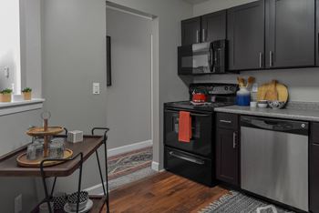 a kitchen with stainless steel appliances and black cabinets and a table at The Pointe at St. Joseph Apartments, South Bend, 46617